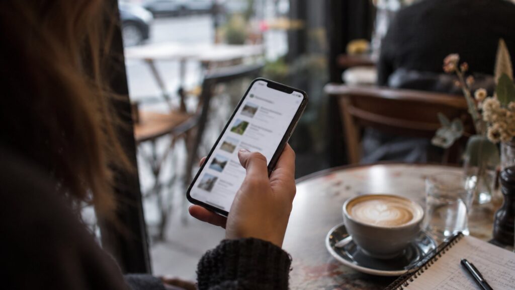 Business owner scrolling a list of service providers on a phone at a cafe table