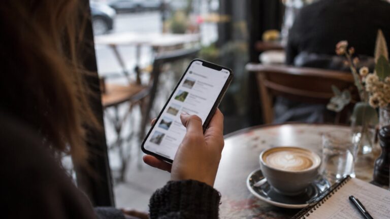 Business owner scrolling a list of service providers on a phone at a cafe table